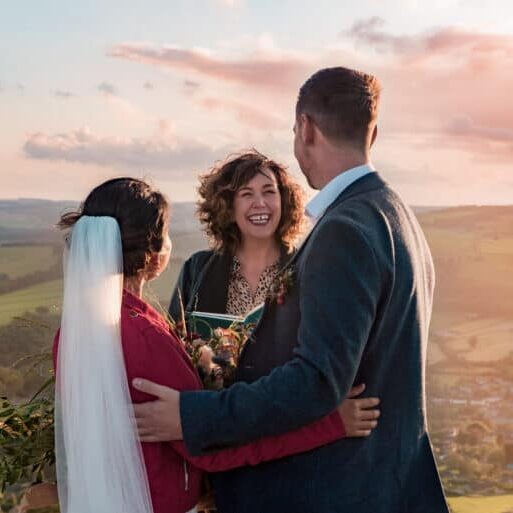 Wedding celebrant marrying couple outside with view of countryside
