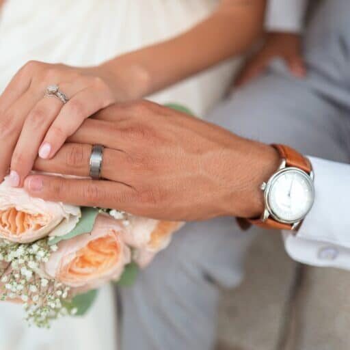 man and woman holding hands on wedding day featuring wedding rings